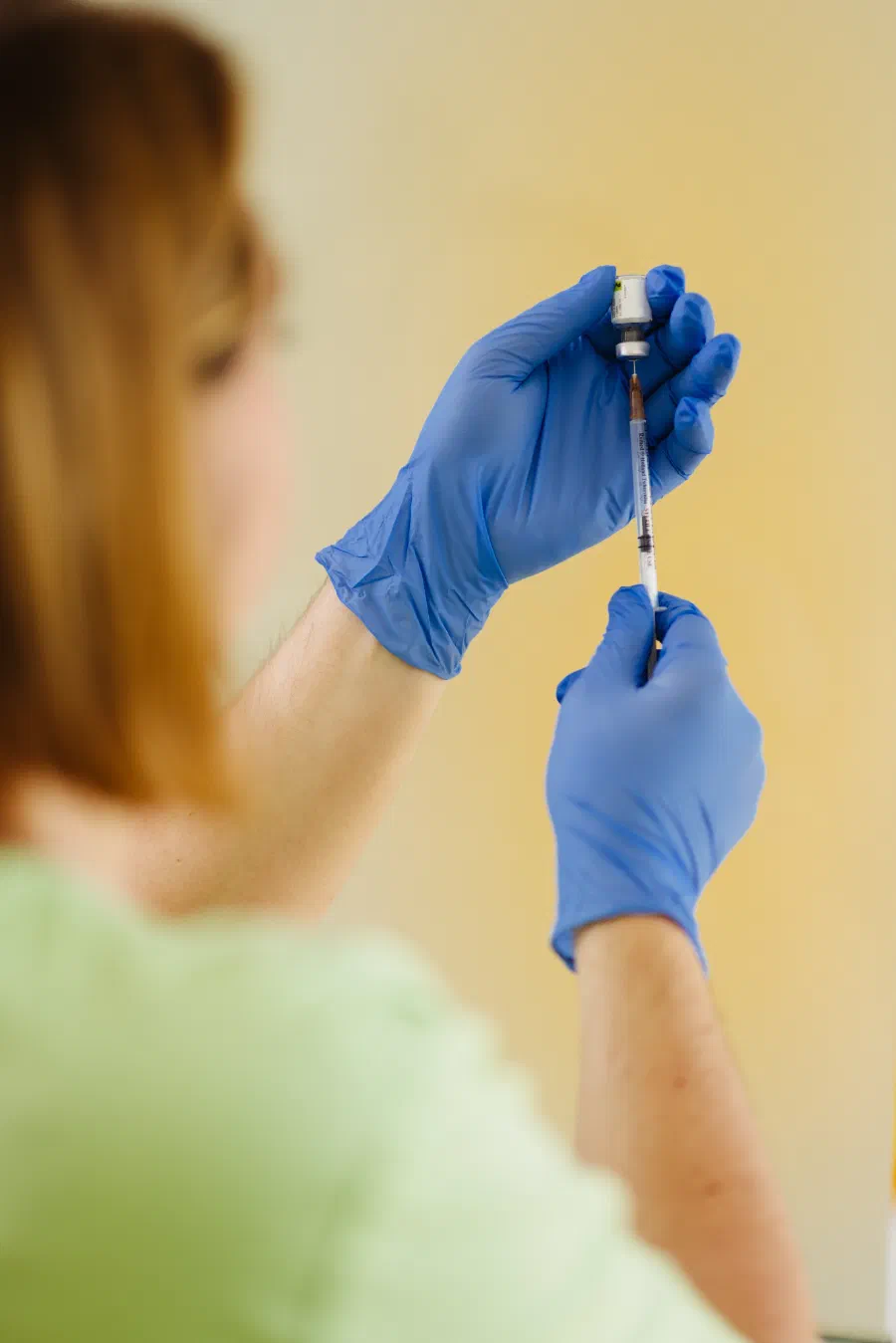 Medizinische Fachangestellte zieht eine Impfdosis in eine Spritze auf